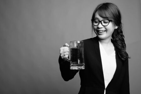 Young beautiful Asian businesswoman against gray backgroundの写真素材