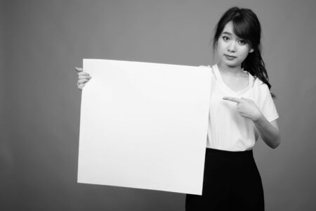 Portrait of young beautiful Asian businesswoman holding whiteboardの写真素材