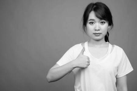 Young beautiful Asian woman against gray background