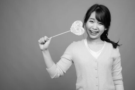 Young beautiful Asian woman holding heart shaped lollipopの写真素材