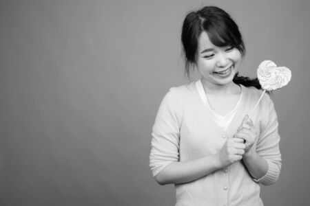 Young beautiful Asian woman holding heart shaped lollipopの写真素材