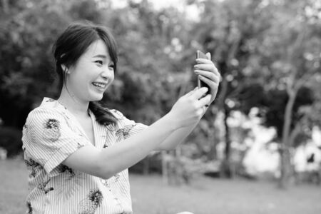 Young beautiful Asian tourist woman relaxing at the parkの写真素材