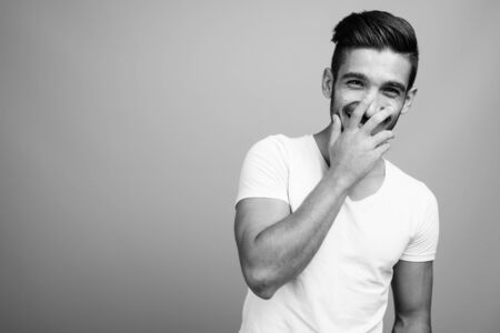 Young handsome Persian man against gray background