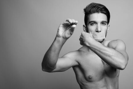 Young handsome Persian man shirtless against gray background
