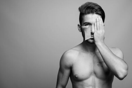 Young handsome Persian man shirtless against gray background