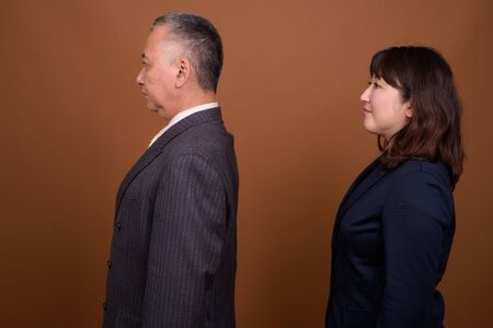 Profile view of mature Asian businessman and mature Asian businesswoman together