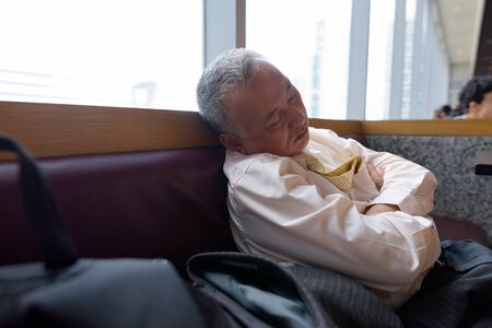 Portrait of mature Japanese businessman relaxing inside the restaurant at the mallの写真素材