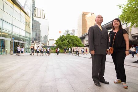 Mature Asian businessman and mature Asian woman exploring the city togetherの写真素材