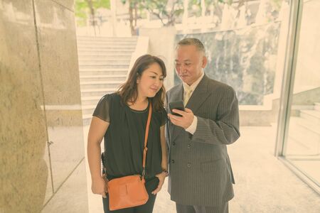 Mature Asian businessman and mature Asian woman exploring the city together