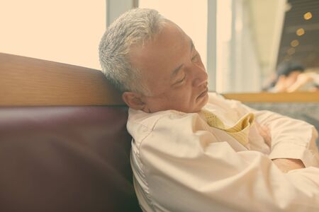 Mature Asian businessman relaxing inside the restaurantの写真素材