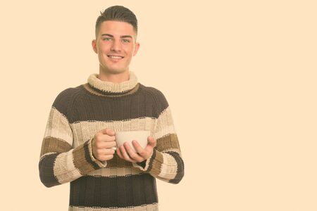 Studio shot of young handsome Hispanic man isolated against white backgroundの写真素材