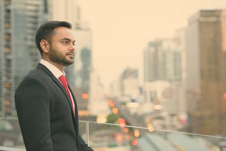 Young bearded Indian businessman against view of the cityの写真素材