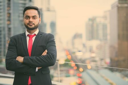 Young bearded Indian businessman against view of the cityの写真素材