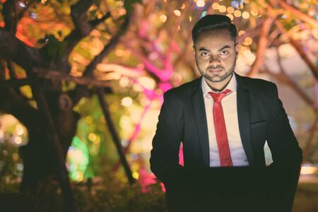 Young bearded Indian businessman against view of the city at night