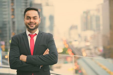 Young bearded Indian businessman against view of the cityの写真素材