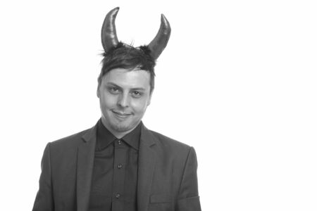 Studio shot of happy Caucasian businessman wearing devil horns