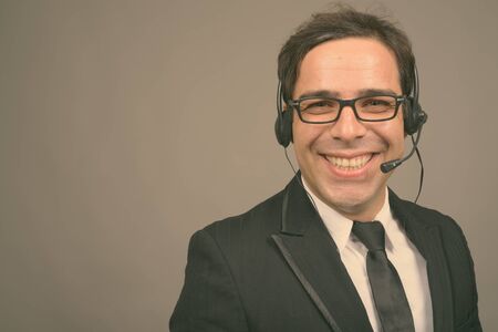 Handsome Persian businessman working as call center representative against gray backgroundの写真素材