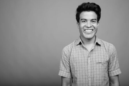 Portrait of young Asian businessman against gray backgroundの写真素材