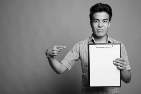 Portrait of young Asian businessman against gray backgroundの写真素材