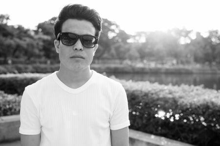 Young Asian man wearing sunglasses while relaxing at the park