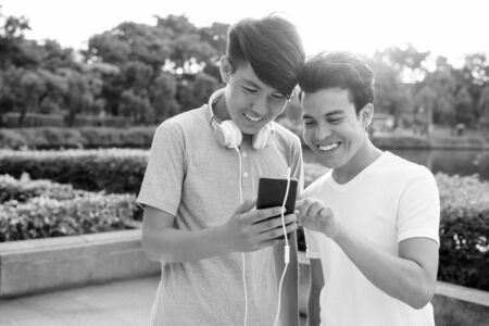 Young Asian man and young Asian teenage boy at the park togetherの写真素材