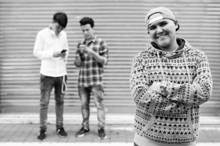 Three young Asian men standing in the streets outdoorsの写真素材