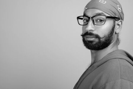Portrait of young handsome bearded Indian man with eyeglasses