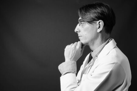 Mature handsome Italian man doctor against gray backgroundの写真素材