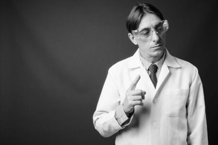 Mature handsome Italian man doctor wearing protective glasses