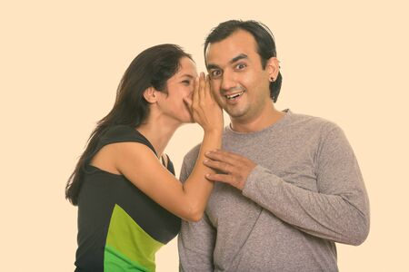 Happy Persian couple smiling while woman whispering to man