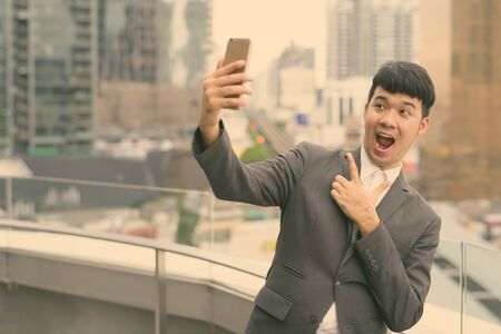 Young Asian businessman against view of the city