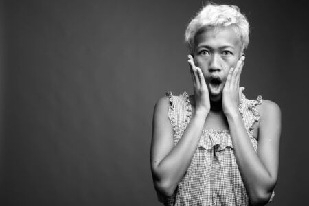 Young beautiful rebellious woman with short hair against gray background