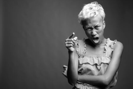 Young beautiful rebellious woman with short hair against gray backgroundの写真素材