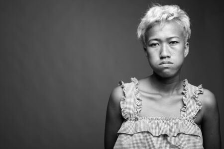 Young beautiful rebellious woman with short hair against gray backgroundの写真素材