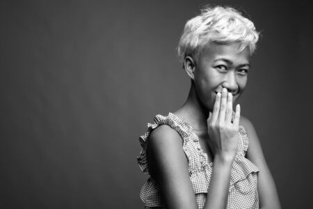 Young beautiful rebellious woman with short hair against gray backgroundの写真素材