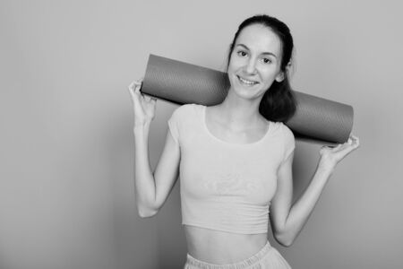 Young beautiful woman ready for gym against gray backgroundの写真素材