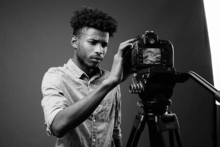 Young handsome African man against gray background