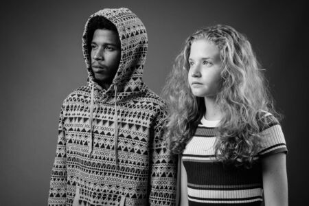 Young African man with teenage girl together against gray backgroundの写真素材