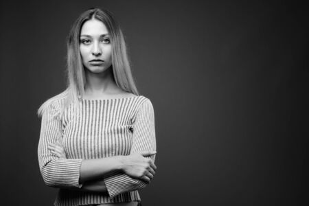 Studio shot of young beautiful woman against gray backgroundの写真素材