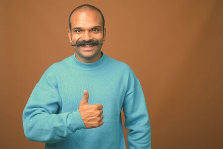 Indian man with mustache against brown background