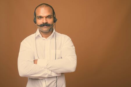 Indian businessman wearing headset against brown background
