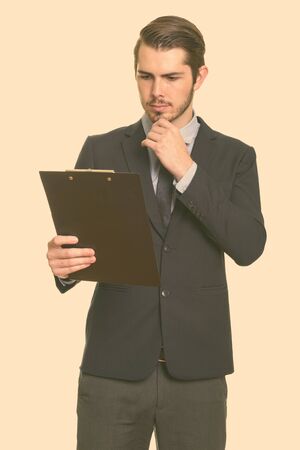 Young handsome Caucasian businessman reading clipboard while thinkingの写真素材