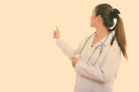 Back view of young Asian woman doctor showing something on the wallの写真素材