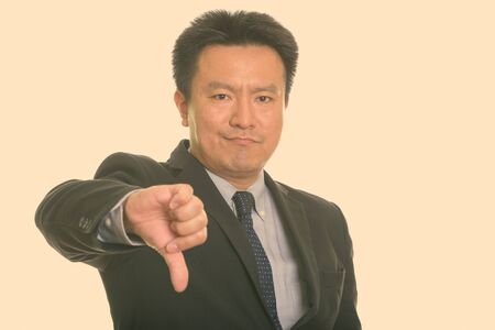 Studio shot of Japanese businessman giving thumb down