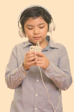 Cute Japanese boy listening to music while using mobile phoneの写真素材