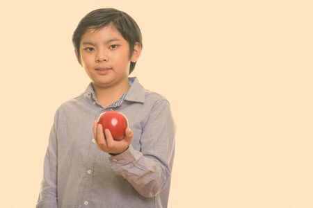 Studio shot of cute Japanese boy holding red appleの写真素材