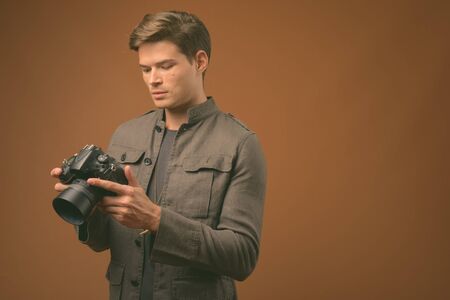 Studio shot of young handsome man against brown background