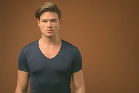 Studio shot of young handsome man against brown background