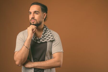 Young bearded Indian man against brown backgroundの写真素材