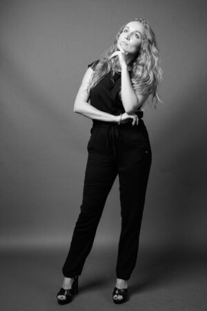 Young beautiful businesswoman with long wavy blond hair against gray backgroundの写真素材